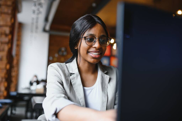 Focused young african american businesswoman or student looking at laptop, serious black woman working or studying with computer doing research or preparing for exam online - Photo, image