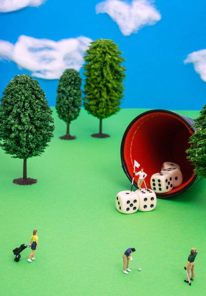 Una escena conceptual diorama de jugadores de golf en miniatura utilizando dados como el agujero - Foto, imagen
