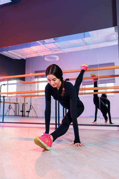 Una giovane donna sportiva in piedi con una gamba sollevata sulla ringhiera sta facendo spago. Allungare i muscoli. Allungamento - Foto, immagini