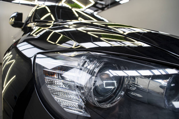 Scheinwerfer eines schwarzen, großen, aggressiven Autos mit Neonreflexen. - Foto, Bild