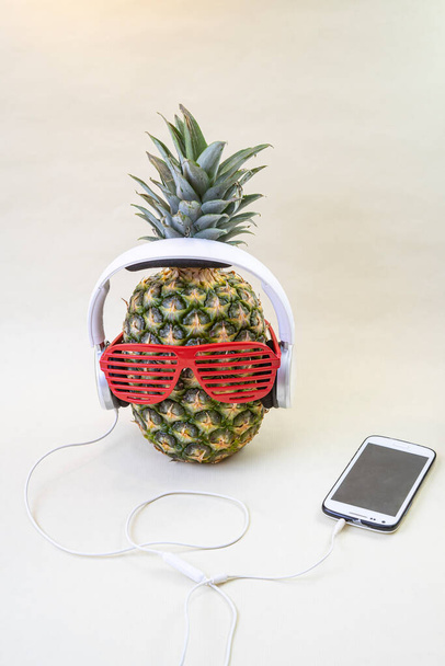 Ananas w okularach disco party, białe słuchawki i smartfon. Koncepcja partii tropikalnej. - Zdjęcie, obraz