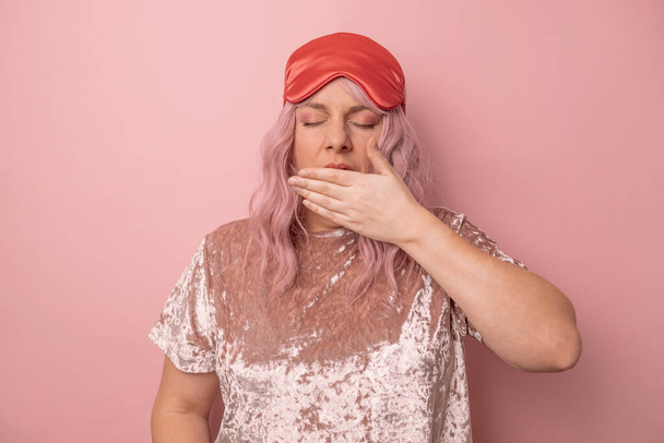 Mulher de cabelo rosa cansado sonolento cobre boca e bocejos isolados sobre fundo rosa. - Foto, Imagem