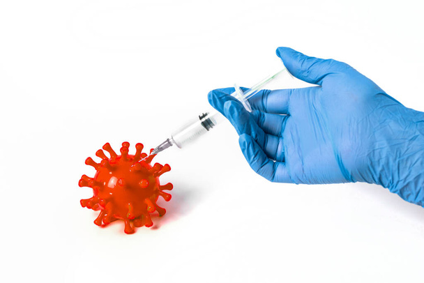 Oltás. Egy orvos keze a kesztyűben befecskendezi a vakcinát egy koronavírussejtbe.. - Fotó, kép
