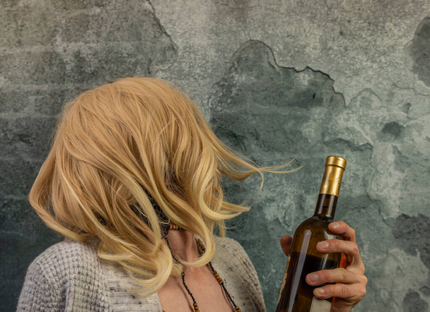 Blond hair woman with bottles of alcohol near old brick wall - Фото, зображення