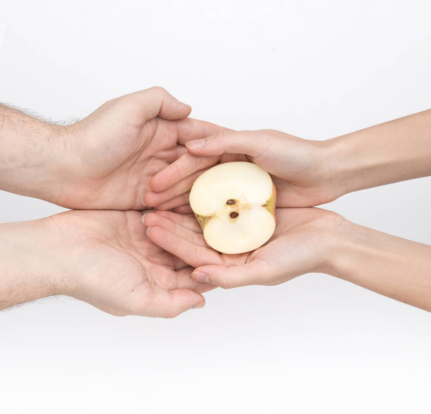 Жіночі руки, що тримають яблуко з насінням, безпечними, обійнятими руками чоловіка в плоскій лінії
 - Фото, зображення