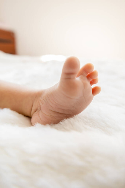 baby's bare foot on a bed, details of an infant's body part, toes in studio concept new member of family and innocence, lifestyle - Photo, Image