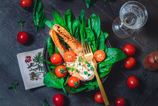 A plate with fresh green raw spinach and fried wild salmon, tomatoes and cream cheese sauce  - Fotoğraf, Görsel