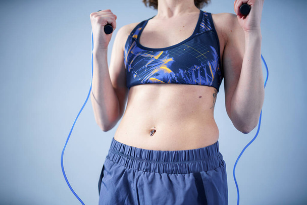 Smiling sportswoman posing with a skipping rope. Female with muscular body posing with jump rope. Fitness model. Body positivity, sport, fitness concept. Healthy lifestyle. Fit woman with jump rope. - Photo, Image
