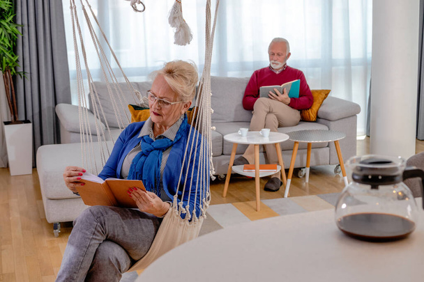 Υπέροχο ζευγάρι ηλικιωμένων που ξεκουράζονται και διαβάζουν στο σπίτι. - Φωτογραφία, εικόνα