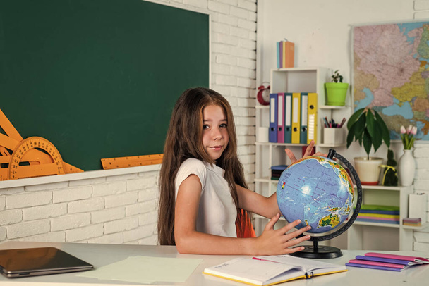 kid in classroom school with blackboard and geography globe, education - Photo, image