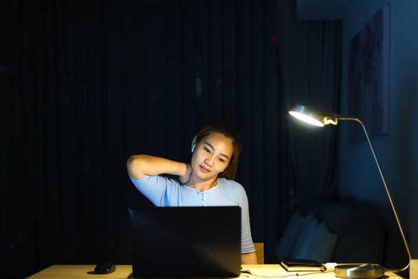 Asiatinnen dehnen sich faul, während sie abends lange vor dem Computer im heimischen Wohnzimmer arbeiten. - Foto, Bild