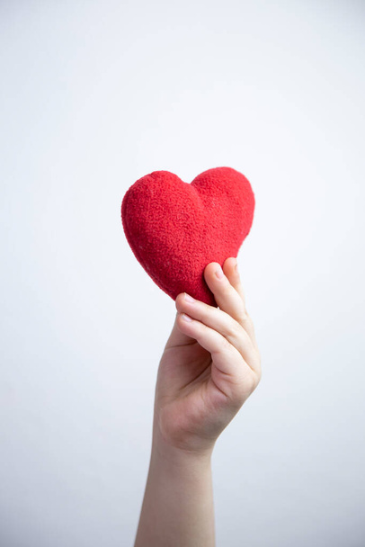 Mano de niño sosteniendo un corazón rojo, fondo blanco. concepto de vida sana y amor   - Foto, imagen