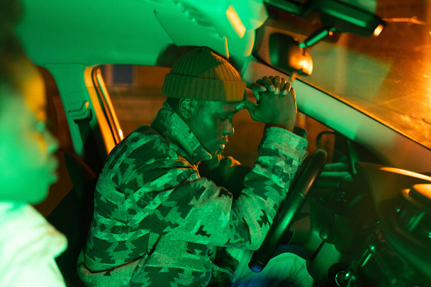 przygnębiony Afrykanin siedzi w samochodzie z dziewczyną w nocy, sfrustrowany czarny facet w samochodzie - Zdjęcie, obraz