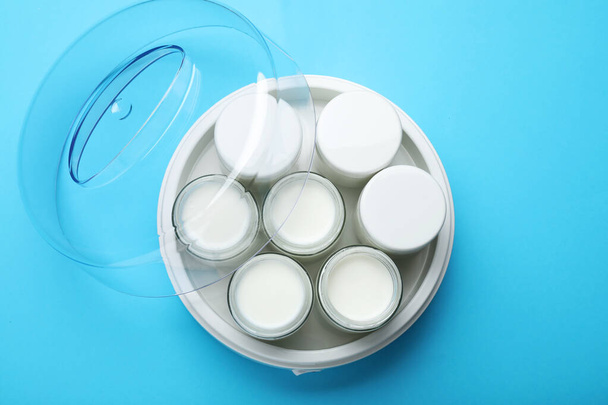 Modern yogurt maker with full jars on light blue background, top view - Photo, Image