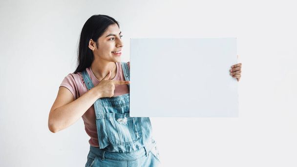 young latin woman pointing at copy space in a blank board or banner in Latin America - Photo, Image