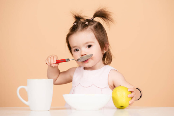 Cute baby food, babies eating. Kid eating healthy food with a spoon at studio, isolated. Funny kids face. - Photo, image