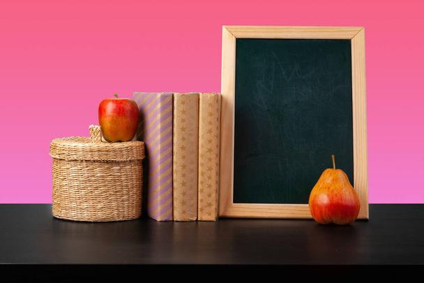 Blackboard and stacked books against colored background - 写真・画像