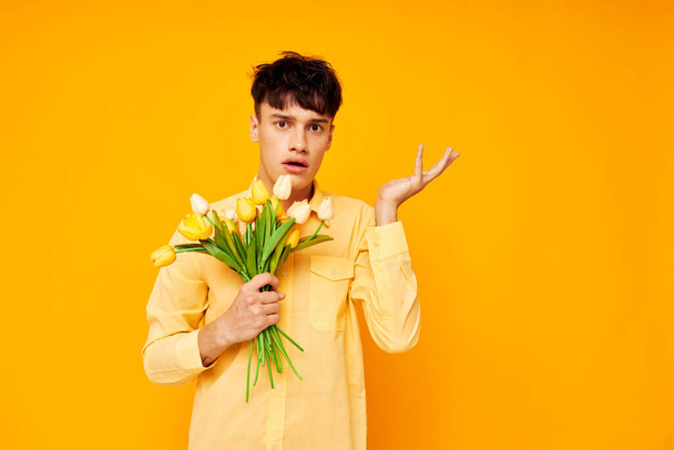 handsome guy with a fashionable hairstyle in yellow shirts with flowers yellow background unaltered - Foto, afbeelding