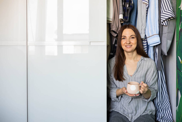 Portrait happy domestic woman posing wardrobe storage organization. Wooden furniture cabinet design - Fotó, kép