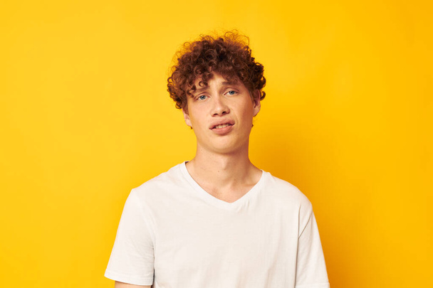 curly red-haired guy in a white t-shirt on a yellow background - Valokuva, kuva