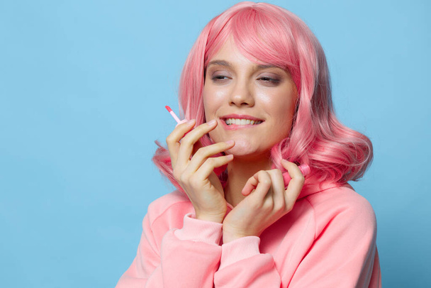 красивая женщина с розовыми волосами с блеском для губ синего фона. Высокое качество фото - Фото, изображение