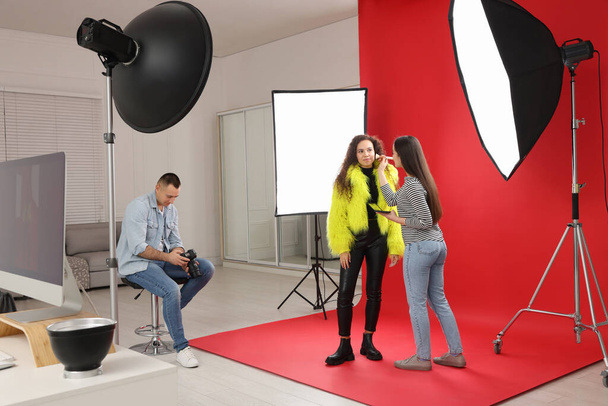 Professional photographer and makeup artist with model in studio - Foto, afbeelding
