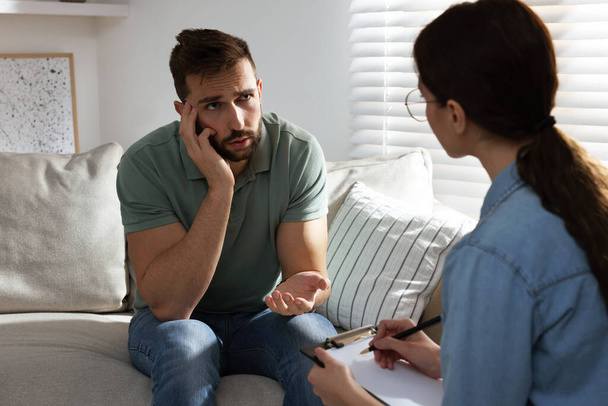 Unhappy man having session with his therapist indoors - Photo, image
