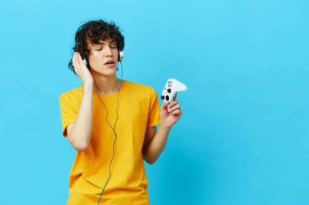 gamer plays with joystick in yellow t-shirts isolated backgrounds - Foto, Bild
