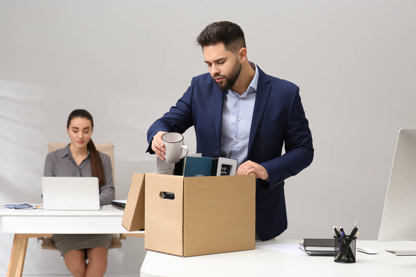 Dismissed man packing personal stuff into box in office - Photo, image