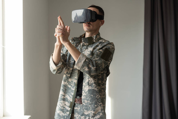 Homme militaire essayant de toucher des objets virtuels tout en portant un casque VR. Handicap et gadgets modernes. - Photo, image