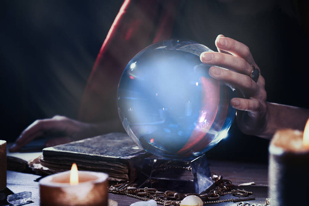 Soothsayer using crystal ball to predict future at table in darkness, closeup. Fortune telling - Fotó, kép