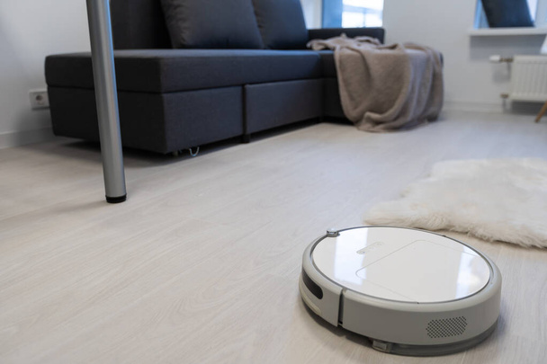 Aspirapolvere robotico su pavimento in legno laminato in camera da letto
. - Foto, immagini