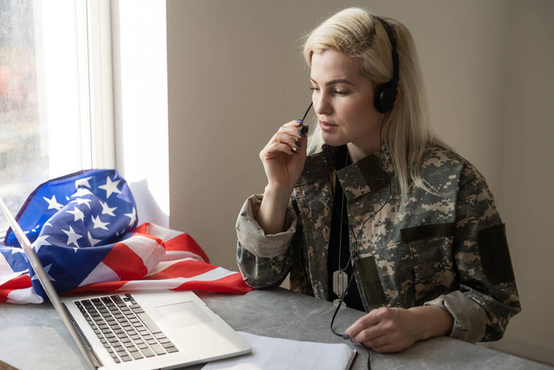 Νεαρή γυναίκα στρατιώτης που εργάζεται με φορητό υπολογιστή στο κτίριο έδρα. - Φωτογραφία, εικόνα