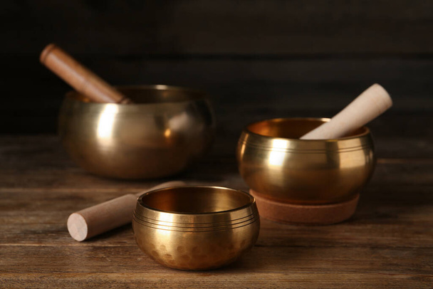 Golden singing bowls with mallets on wooden table - Foto, immagini