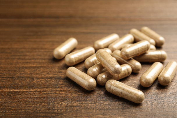 Dietary supplement capsules on wooden table, closeup. Space for text - Foto, imagen