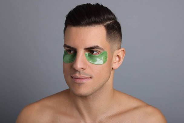 Man with green under eye patches on grey background - Photo, image