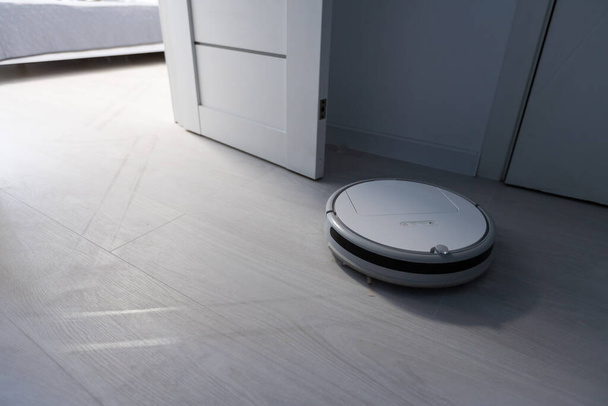 Wireless Robotic vacuum cleaner cleaning a wooden floor in living room - Valokuva, kuva