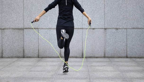 Fitness woman rope skipping against city wall - Zdjęcie, obraz