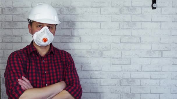 Ritratto di un uomo con un casco da costruzione e un respiratore sul viso. - Filmati, video