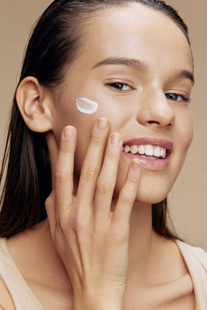 young woman hand near face applying  cream on  isolated background. High quality photo - Φωτογραφία, εικόνα