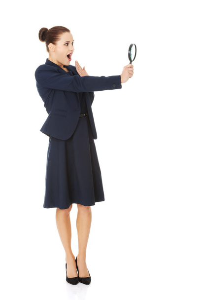 Business woman looking into a magnifying glass - Φωτογραφία, εικόνα