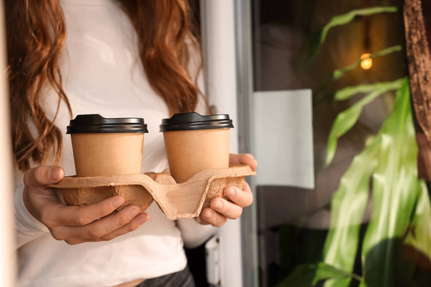 Woman holding paper coffee cups indoors, closeup. Space for text - 写真・画像