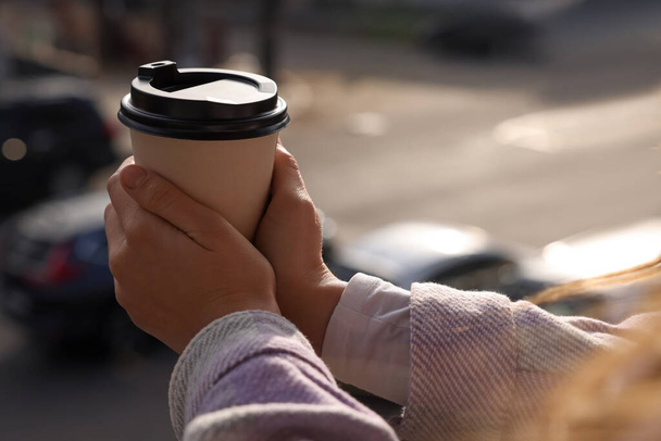 Woman holding paper coffee cup outdoors, closeup - Фото, изображение