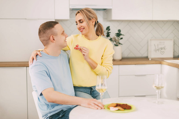 Una pareja joven durante una cena romántica en la cocina durante la celebración del Día de San Valentín o aniversario - Foto, Imagen