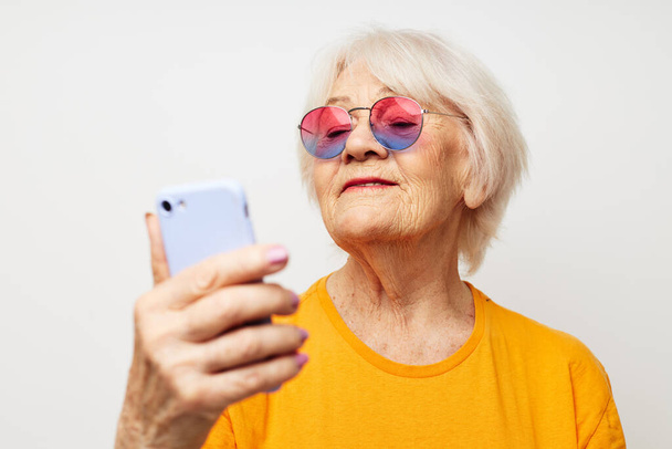 smiling elderly woman in a yellow t-shirt posing communication by phone close-up emotions - Фото, зображення