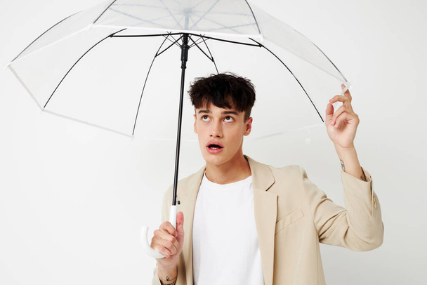 Photo young boyfriend holding an umbrella in the hands of posing fashion light background unaltered - Valokuva, kuva