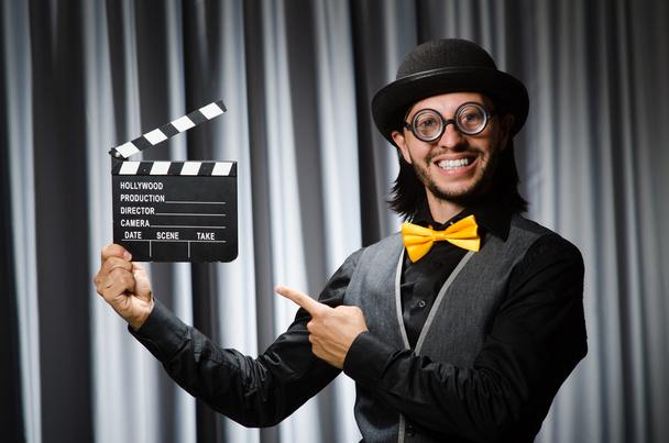 Funny man with movie board against curtain - Photo, Image
