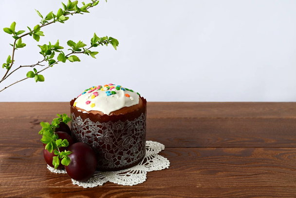 Traditional Easter cake with decorative glaze. Orthodox food after fasting on the Easter holiday. Red-painted chicken eggs on a white knitted tablecloth on a wooden table - Photo, image
