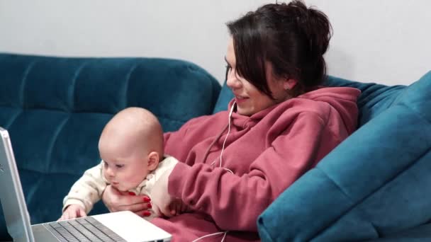 Mãe freelancer sentada no sofá no escritório em casa durante o confinamento. Trabalho remoto em casa com uma criança. - Filmagem, Vídeo
