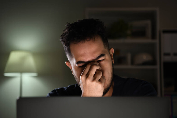 Ich fühle mich gestresst und depressiv. Asiatischer Mann sieht unglücklich, gestresst und müde aus, während er zu Hause spät abends am Computer arbeitet - Foto, Bild